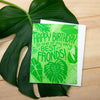 Green birthday card with leaf design on a wooden surface with leaves