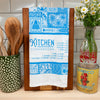 Kitchen towel with 'Kitchen Conversions' text hanging on a wooden block, surrounded by kitchen items.