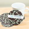 Set of four goose-patterned coasters with a mug on a wooden surface