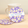 Set of four purple and white coasters with a mug on a wooden surface