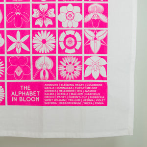 Tea towel with pink and white floral patterns and a list of flower names on a white background.