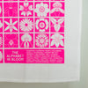 Tea towel with pink and white floral patterns and a list of flower names on a white background.