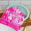 Pink floral towel with text on a green bowl against a tiled wall background