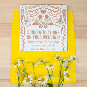 Wedding card with decorative design and yellow envelope on a wooden surface