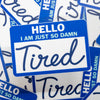 Sticker with 'HELLO I AM JUST SO DAMN Tired' text on a blue border, surrounded by similar stickers.