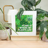 Framed print with 'Home is where my plants are' text on a shelf with plants