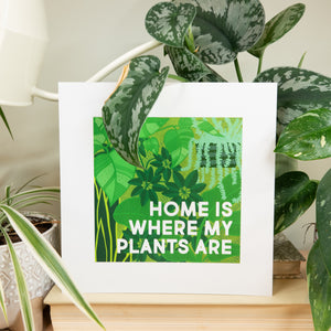 Framed print with 'Home is where my plants are' text in a room with plants