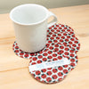 Set of four ladybug patterned coasters with a white mug on a wooden surface