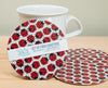Set of four ladybug pattern coasters with a mug on a wooden surface