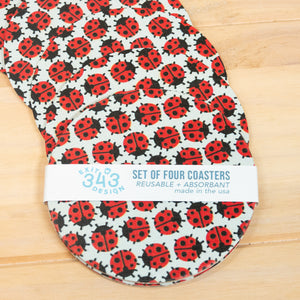 Set of four ladybug pattern coasters with a label on a wooden surface
