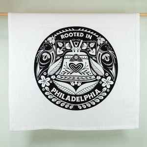 White tea towel with black and white design featuring text 'Rooted in Philadelphia' on a light green background