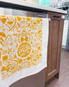 Kitchen towel with pasta-themed design hanging on a kitchen cabinet.
