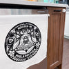 Tea towel with 'Rooted in Philadelphia' design hanging on a wooden kitchen cabinet.