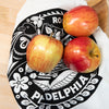 Three apples on a decorative black and white Philadelphia-themed towel.