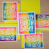 Colorful 'Happy Birthday' cards on a wooden surface