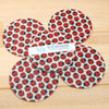 Set of four red and black ladybug patterned coasters on a wooden surface.
