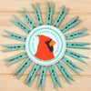 Decorative wall art with teal clothespins arranged in a circular pattern around a cardinal logo.