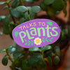 purple sticker that says talks to plants with a small flower